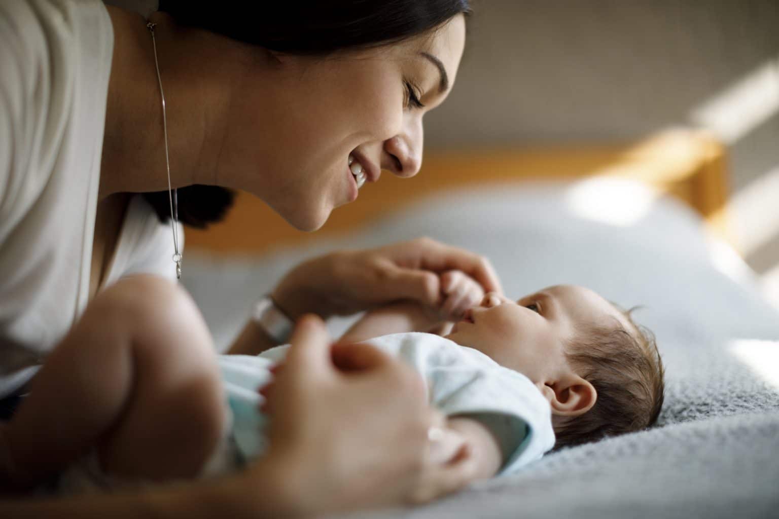 Woman holding hand of very small baby in a hospital room setting